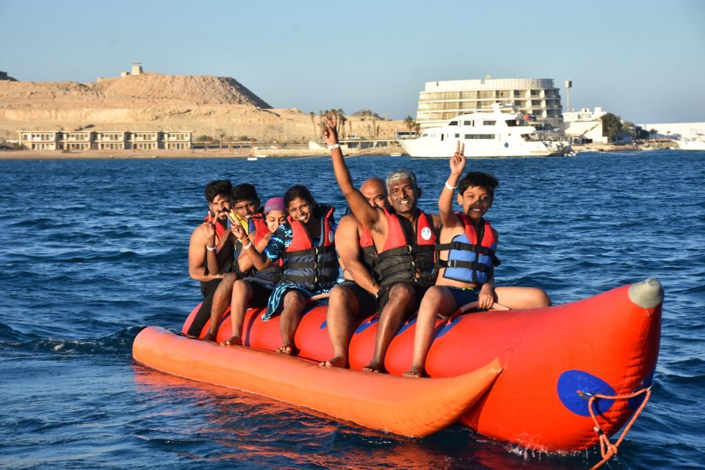 Friends laughing together on an inflatable ride over the sea